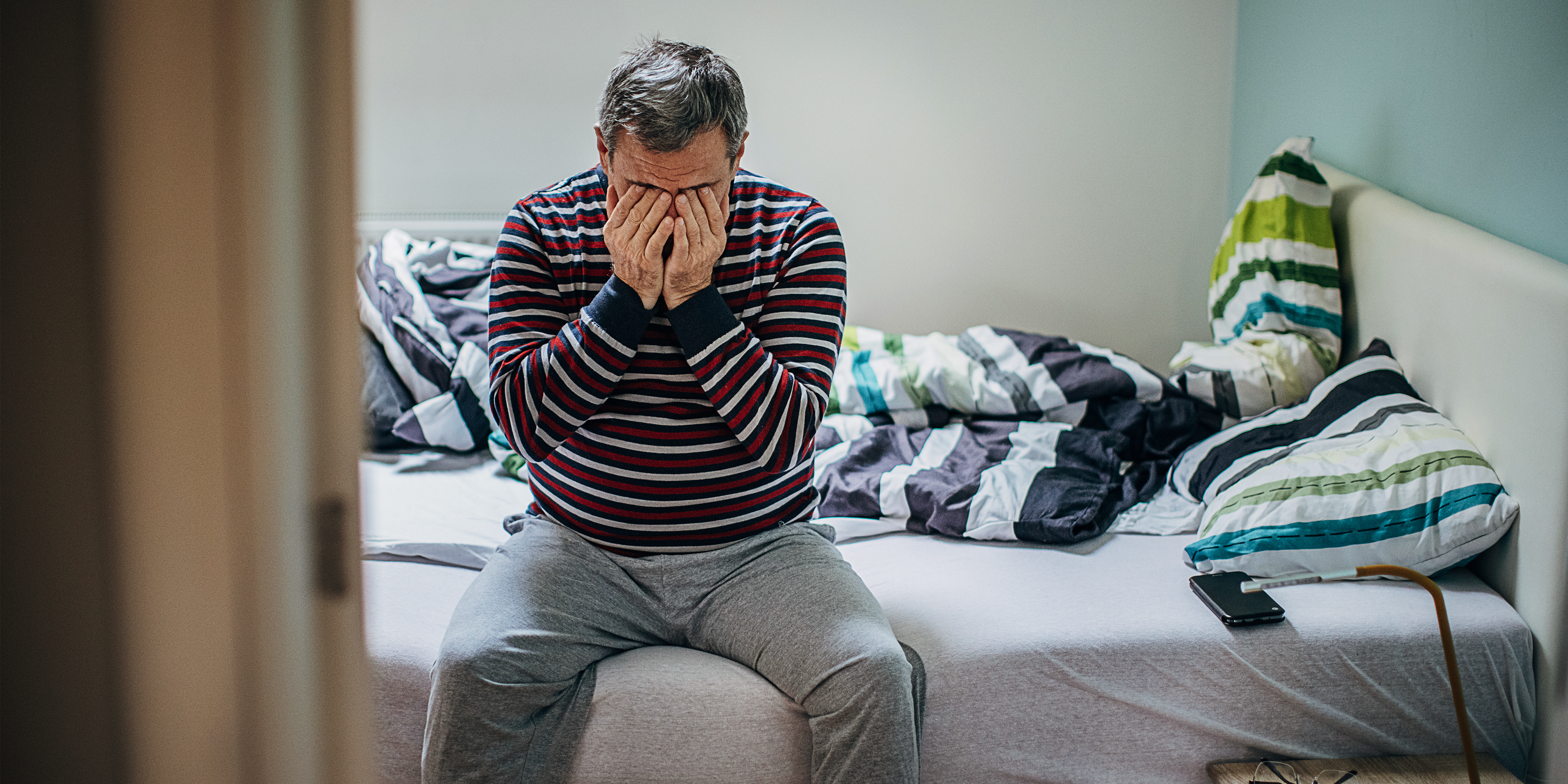 Man sitting on a bed in a homeless shelter.