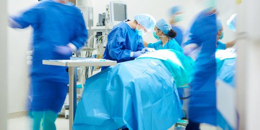 Surgical team in the process of performing emergency surgery. Blurring of some of the surgical staff members denotes urgency.